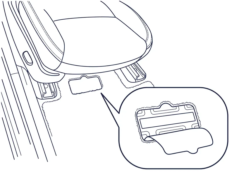 A flap cut in the carpet at the front of the driver's seat, folded back to show the VIN on the floor beneath